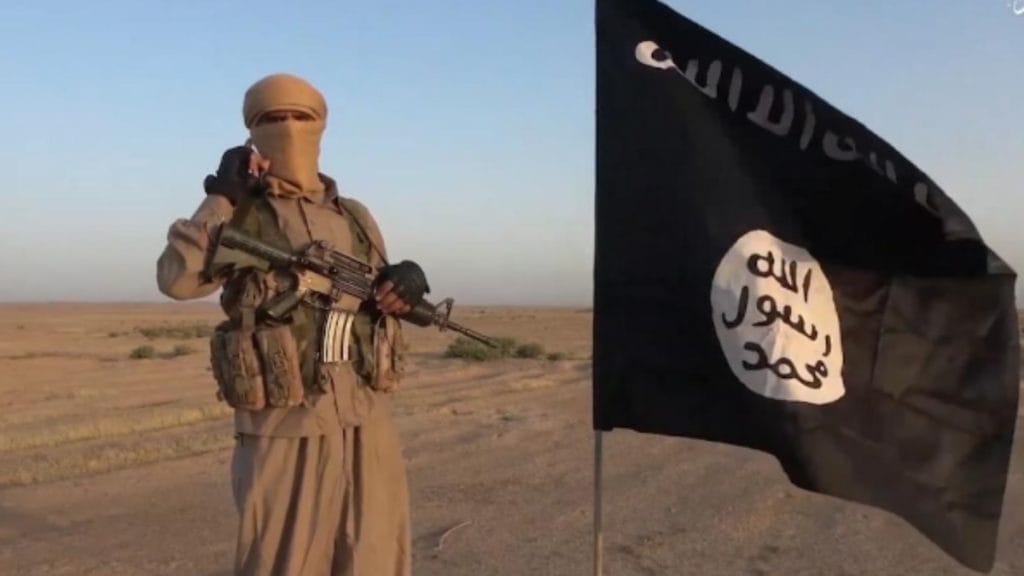 Soldier Holding a Gun by a Flag in Iraq  for ISIS, Terrorism, and Infrastructure Destruction in Iraq